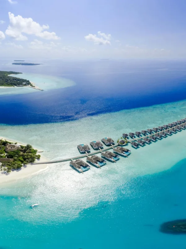 Serene view of Sun Siyam Olhuveli beach in the Maldives, showcasing pristine white sands, crystal-clear waters, and tropical surroundings, ideal for couples enjoying a romantic 4N/5D honeymoon getaway.