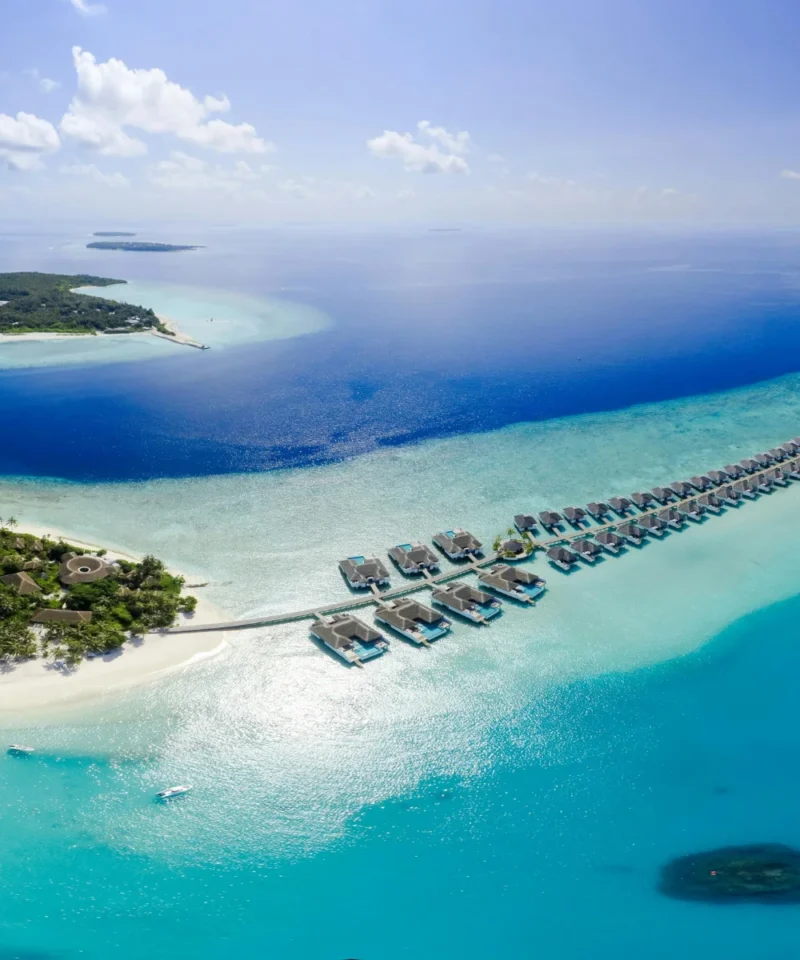 Serene view of Sun Siyam Olhuveli beach in the Maldives, showcasing pristine white sands, crystal-clear waters, and tropical surroundings, ideal for couples enjoying a romantic 4N/5D honeymoon getaway.