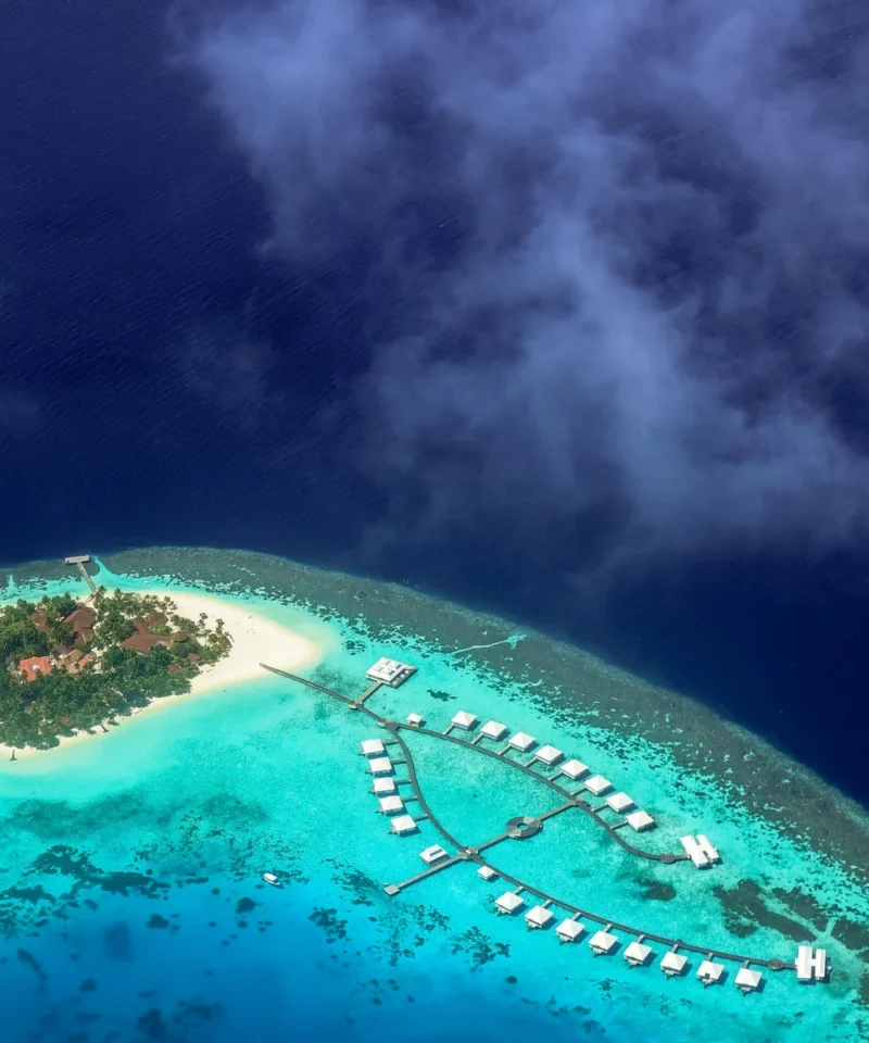 Aerial view of an overwater villa at Sun Siyam Olhuveli in the Maldives, surrounded by turquoise waters and pristine beaches, perfect for couples enjoying a 4N/5D romantic honeymoon filled with luxury, relaxation, and ocean adventures.